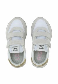Scarpe da ginnastica bianche e grigie chiare con cinturini in velcro, pannelli in rete e un accento dorato sul tallone. L'interno etichettato presenta testo rosa.