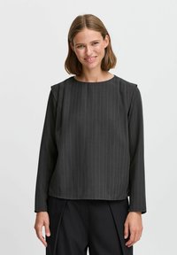 Top nero a maniche lunghe con righe verticali bianche, dotato di scollatura rotonda e dettagli strutturati sulle spalle. Tessuto liscio con una vestibilità comoda.