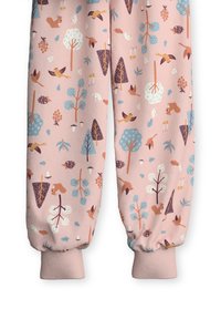 Pink fabric joggers featuring a whimsical pattern of trees, animals, and plants in blue, brown, and white. Cuffs are ribbed at the ankles.