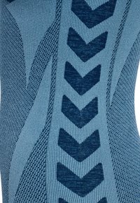 Tissu bleu à motif avec une texture côtelée et des motifs en forme de flèche dans un bleu plus foncé, créant un effet visuel géométrique.