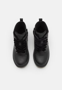 Černé kožené kotníkové boty se šněrováním, bočním zipem a texturovanou gumovou podrážkou. Mají polstrovanou podšívku a poutko na patě.