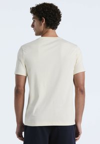 Lichtcrème t-shirt met korte mouwen, gemaakt van zachte katoen, met een klassieke ronde halslijn en een ontspannen pasvorm met een gladde textuur.