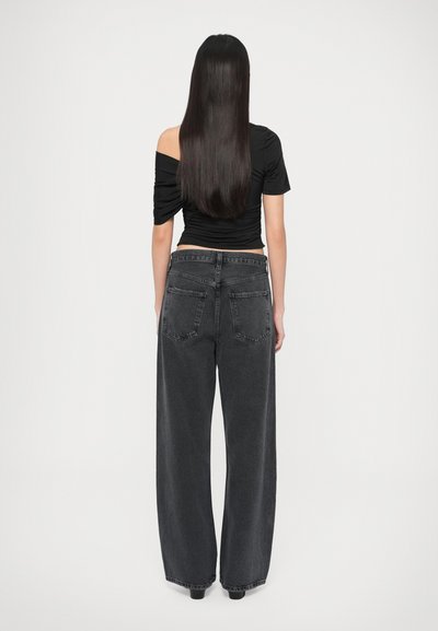 Μαύρο τοπ με ακάλυπτους τους ώμους, με ρυτιδωτό σχέδιο. Συνδυάζεται με φαρδιά, ψηλόμεση, σκούρα γκρι τζιν. Απλές πίσω τσέπες, με ίσια γραμμή στα πόδια.