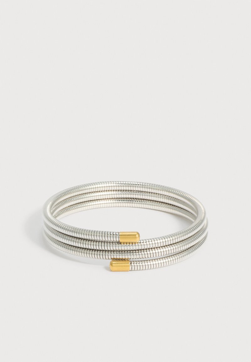 Ευέλικτο ασημένιο βραχιόλι με τρεις θηλιές και χρυσούς τελείωμα σε λευκό φόντο.