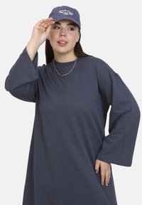 Oversized dark blue long-sleeve dress in soft fabric, paired with a matching cap featuring "Amalfi Coast" embroidered on the front.