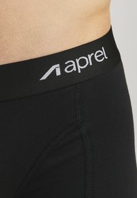 Black underwear with a smooth texture, featuring a wide black waistband with white "aprel" logo and visible stitching details.