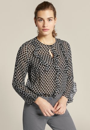 Zijdezwarte blouse met wit scallop patroon, gerimpelde voorkant, ronde halslijn en lange mouwen met elastische manchetten.