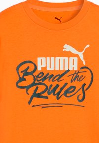 Pomarańczowy t-shirt z bawełny z okrągłym dekoltem. Na froncie grafikę z napisem "PUMA" na białym tle oraz "Bend the Rules" na ciemnoniebieskim tle z logo Pumy.
