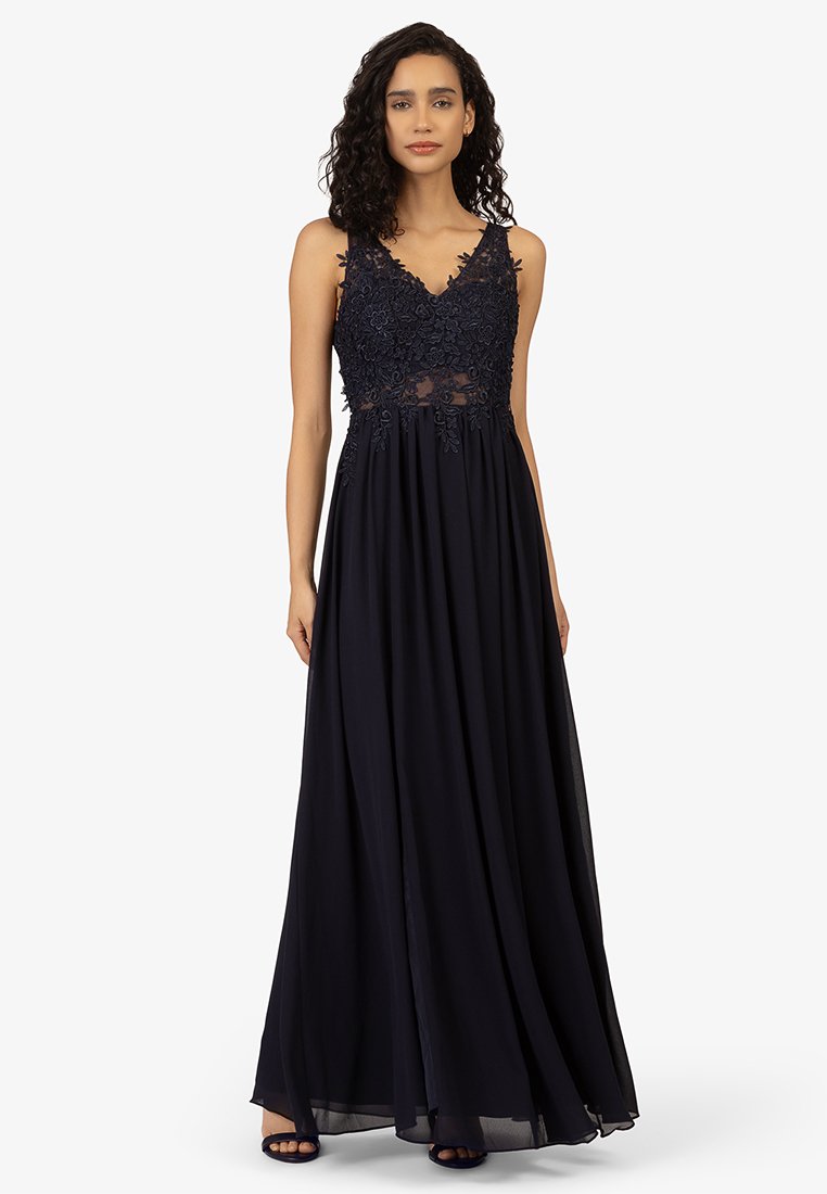 Granatowa suknia wieczorowa z dopasowaną górą, z koronkowym pokryciem w kwiaty, przeźroczystym środkowym panelem i zwiewną, sięgającą do podłogi spódnicą.