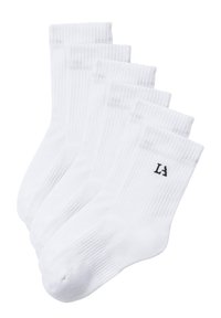Cinco pares de calcetines de algodón blanco con puños acanalados, punta y talón reforzados, y un pequeño logo negro en un calcetín de cada par.