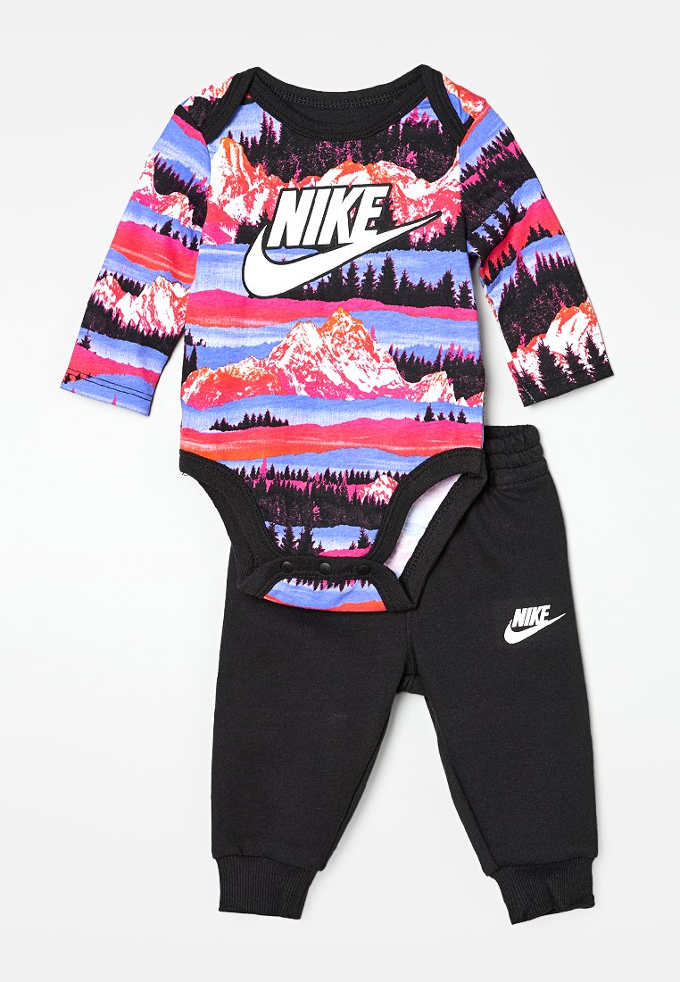 Body avec un design de paysage montagneux multicolore et des finitions noires, associé à un pantalon noir affichant le logo blanc de Nike sur les deux articles.