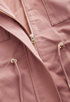 Giacca rosa chiaro con zip dorata, cordini e doppie tasche sul petto, realizzata in un tessuto liscio con una leggera texture opaca.