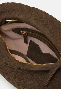 Borsa in suede marrone con una trama intrecciata intricata, dotata di una zip dorata e un interno rosa chiaro. Include una piccola tasca e un’etichetta all'interno.