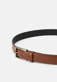 Brown leather belt with a sleek black underside, featuring a rectangular silver metal buckle and multiple holes for adjustments.
