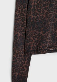 Dolga majica v rjavi barvi z črnim leopardjim vzorcem. Gladka tkanina z šivi ob robu in zapestjih za urejeno zaključek.