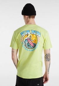 Vaaleanvihreä lyhythihainen t-paita, jossa on suuri grafiikka, joka esittää luurankoa surffaamassa, ja tekstinä "VANS WAVES SMASHER" sinisin ja vaaleanpunaisin tehostein.