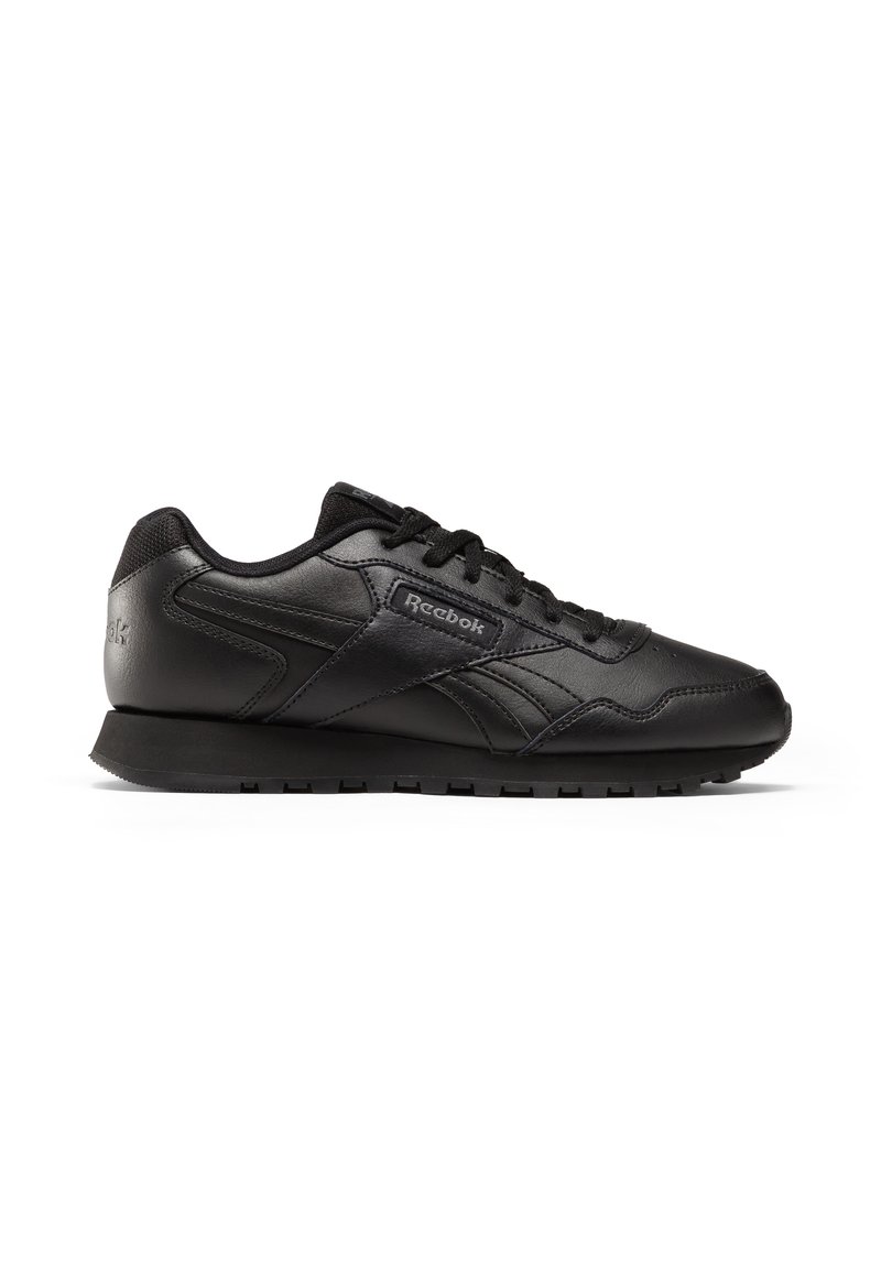 Czarne buty sportowe wykonane z gładkiego materiału syntetycznego, z niskim profilem, zaokrąglonym noskiem oraz teksturowanymi akcentami po bokach i na pięcie.