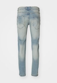 Jeans de mezclilla de color azul claro y desgastados, mostrados desde atrás, con dos bolsillos traseros y pliegues sutiles a lo largo de la tela.