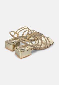 Gouden sandalen met hoge hakken en straps, met een vierkante blokhak, voorzien van metallic straps en een gladde, glanzende oppervlakte.