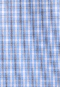 Tissu bleu clair avec un motif à carreaux blanc et bleu marine, montrant une texture tissée et des lignes espacées uniformément.