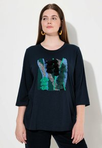 Dunkelblauses T-Shirt mit rundem Halsausschnitt und Dreiviertelärmeln, das farbenfrohe bestickte Quasten und Muster auf der Vorderseite aufweist.