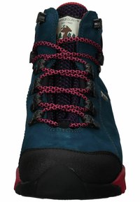 Wandelboot in turquoise suede met een zwarte rubberen neus en een rode accentzool. Beschikt over zwarte oogjes en roze en paarse gestructureerde veters.