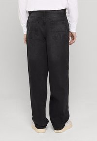 Mustad teksapüksid lõdva lõikega, millel on kaks tagataskut ja vöökoht. Sile tekstuur kerge läikega.