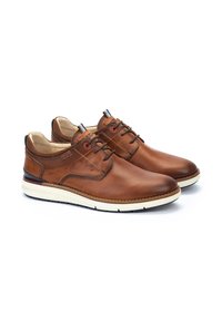Zapatos de cuero marrón con cordones y un acabado suave, suela beige en contraste y una textura sutil en el talón. Detalles rojos en los cordones.