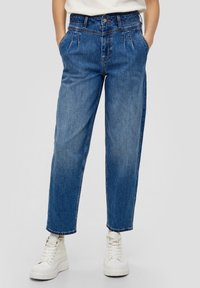 Light blue denim jeans with a relaxed fit, featuring a high waist, pleats, and side pockets, paired with white high-top sneakers.