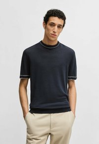 Navy short-sleeve sweater with a crew neckline, featuring contrasting white trim on collar and sleeves, made from a soft knit fabric.