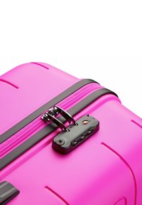 Hard-shell pink suitcase with a textured finish, black zipper, and TSA-approved locking mechanism. Features grooves for easy grip.