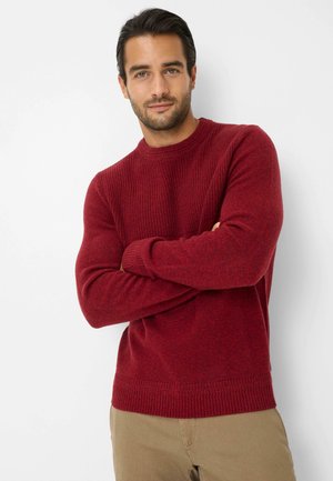 Maglione rosso lavorato a maglia con scollatura a girocollo e trama a coste; presenta maniche aderenti e un orlo con dettagli a coste.