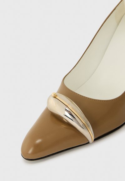 Chaussure en cuir marron à bout pointu avec un accent métallique proéminent arborant une finition dorée et argentée, texture lisse et surface vernissée.