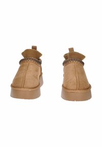 Stivali alla caviglia in suede beige con polsini in maglia, dettagli testurizzati e suola in gomma spessa. Presentano un asola per un facile indossamento.