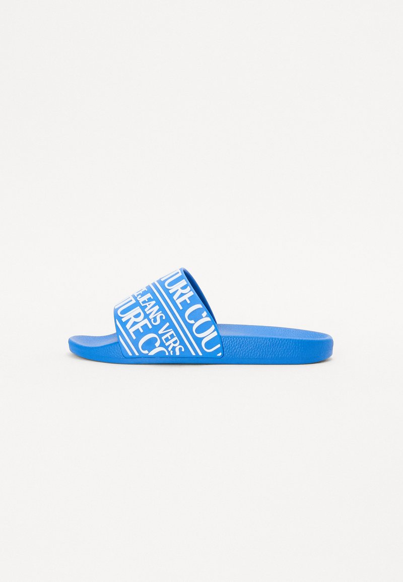 Μπλε σανδάλια με ευρεία λωρίδα που διαθέτει λευκό κείμενο και γραφικά σχέδια. Φτιαγμένα από απαλό, ευέλικτο υλικό με υφή στο πέλμα.