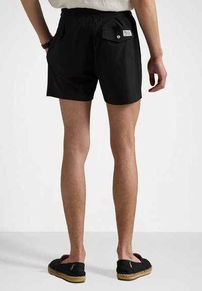 Svarte shorts med elastisk midje, sidelommer og en baklomme med knappelukking og et merke.