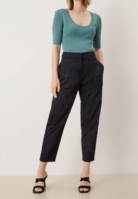 Teal kortärmad stickad topp med ribbat mönster och rundad halsringning. Svarta skräddarsydda byxor med smal passform och sidofickor. Svarta sandaler med blockklack.