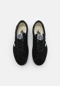 Sneakers in camoscio nero con design low-top, dotate di lacci neri, una striscia laterale bianca e targhette con logo visibili sulla linguetta.