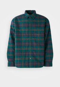 Zöld és sötétkék kockás flaneling gombos záródással, gallérral és egyetlen mellzsebbel. Sárga és bordó kiegészítő csíkokkal rendelkezik.