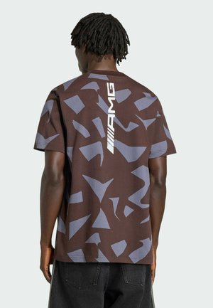 Brązowy t-shirt z geometrycznym wzorem w jasnoniebieskim kolorze, krótkie rękawy, prążkowany okrągły dekolt i pionowe białe logo AMG na plecach.