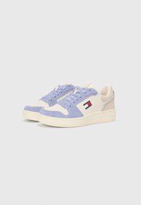 Adidași cu vârful și limba din suede lila, corp din piele crem și accente bej; prezintă șirete texturate și o etichetă cu logo.