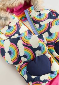 Chaqueta acolchada colorida con un patrón de arcoíris y nubes, detalles en azul marino, capucha forrada de piel y un interior rosa brillante.