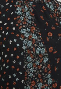 Tela negra con un patrón floral que presenta flores naranjas y azul claro, texturizada con diferentes densidades de flores. Detalle de escote elástico.