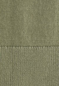 Tissu tricoté dans une olive atténuée, présentant un motif côtelé texturé en bas et une finition plus lisse au-dessus.