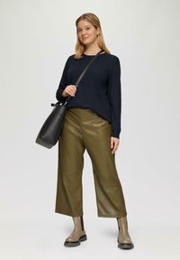 Marineblauwe trui, olijfgroene imitatieleren wijde broek, grijze enkellaarsjes met zwarte accenten en een zwarte emmer tas.