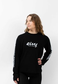 Zwarte langemouwen T-shirt met witte logotekst op de borst en mouwen, gemaakt van een zachte stof met een ontspannen pasvorm.