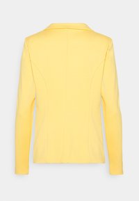 Gul blazer med långa ärmar, slagkrage, skräddarsydd passform och detaljerad sömnad. Slät tyg med minimal textur, bakvy visas.