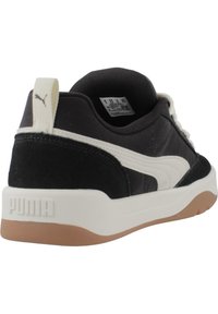 Sneakers neri in suede e materiale sintetico con dettagli bianchi, linguetta imbottita e suola in gomma marrone. Logo del brand sul tallone e sul lato.