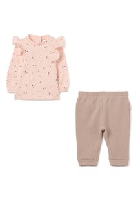 Blusa de manga larga rosa claro con puntos rojos y beiges, hombros con volantes; pantalones beige de canalé con cintura elástica y bolsillos laterales.