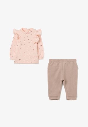 Lichtroze lange mouwtop met rode en beige stippen, gerimpelde schouders; beige ribbelbroek met elastische tailleband en zijzakken.